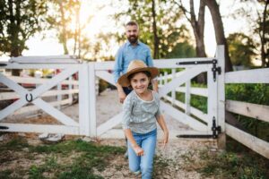 A father with small daughter walking outdoors on family farm