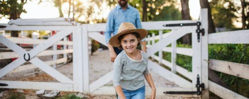 A father with small daughter walking outdoors on family farm